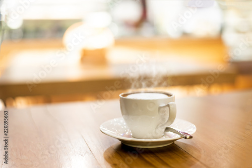 Hot cup of coffee or hot cappuccino on wooden table at coffee shops in blurry background and golden light , this image in coffee and still life concept