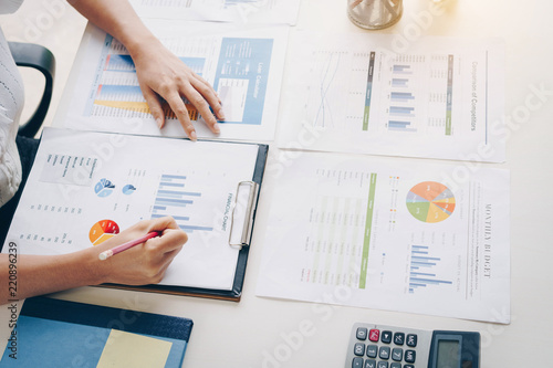 Businesswoman using a calculator to calculate the numbers discussing the charts and graphs showing the results of their successful. Accounting,Finances and economy concept.