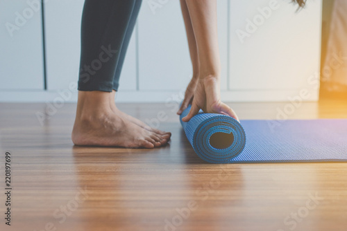 Woman hand rolling or folding yoga mat after a workout