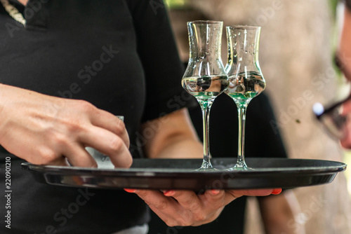 Two glasses of liquor or grappa on a plate served in a german biergarten of a vineyard