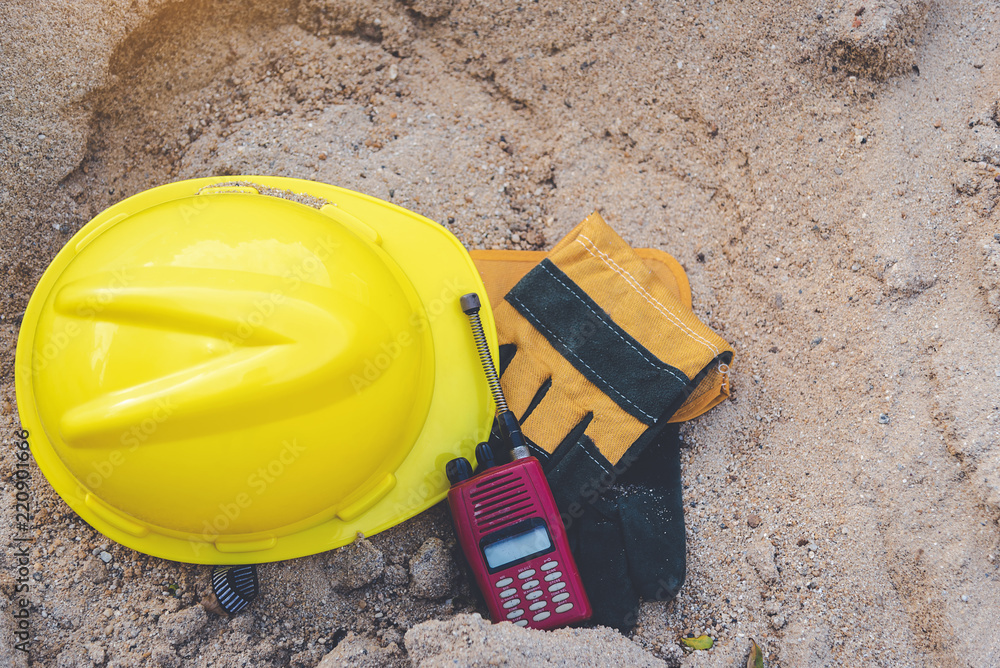 Yellow helmets, gloves, radio communication and house miniature wood on the sand pile. Yellow helmets, gloves, radio communication and house miniature wood on the sand pile.