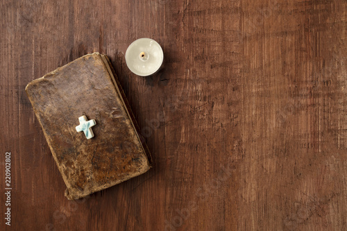 Old bible with a cross and a candle on a dark background with copy space