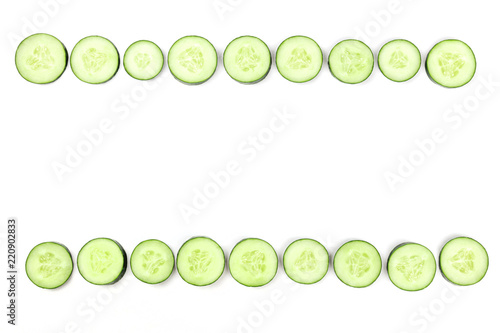 Cucumber slices forming a frame on a white background with copyspace