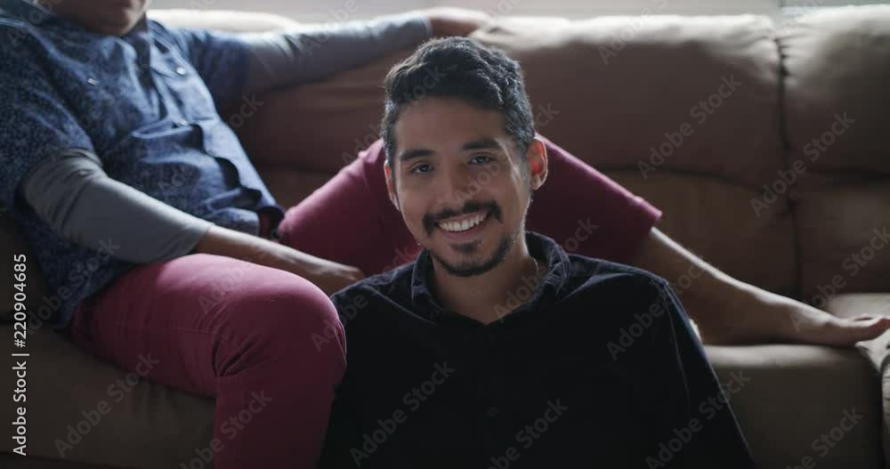 Hispanic Gay Couple Holding Hands On Sofa at Home Hispanic Gay Couple Holding Hands On Sofa at Home