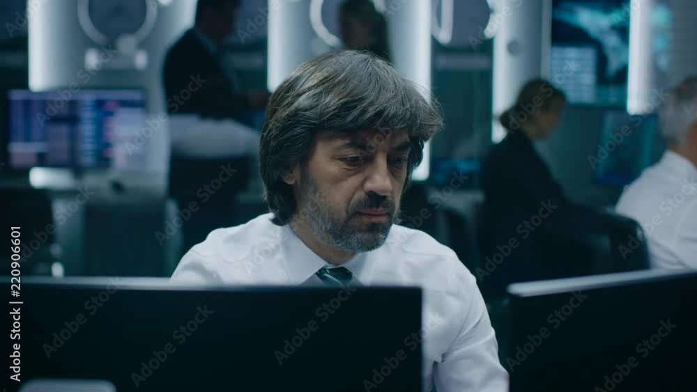 Professional Operators Working On Computers in System Control Room. Secret Government Agency Analysts Doing Research, Conducting Cyber Security Investigation. Professional Operators Working On Computers in System Control Room. Secret Government Agency Analysts Doing Research, Conducting Cyber Security Investigation.