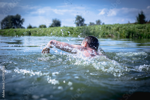 Fototapeta Naklejka Na Ścianę i Meble -  The young man swimming in the river