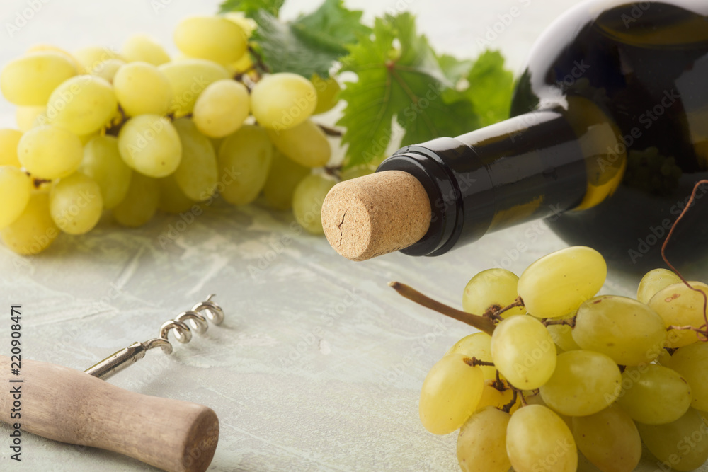 Obraz premium Bottle of white wine, grape and corks on wooden table