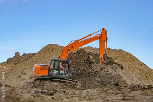 Excavator at the construction site pours a pile of soil