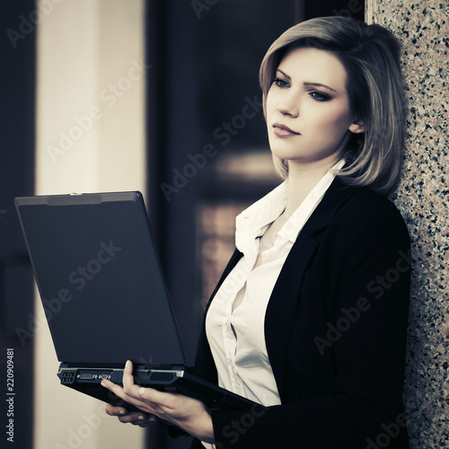 Young business woman using laptop at office building