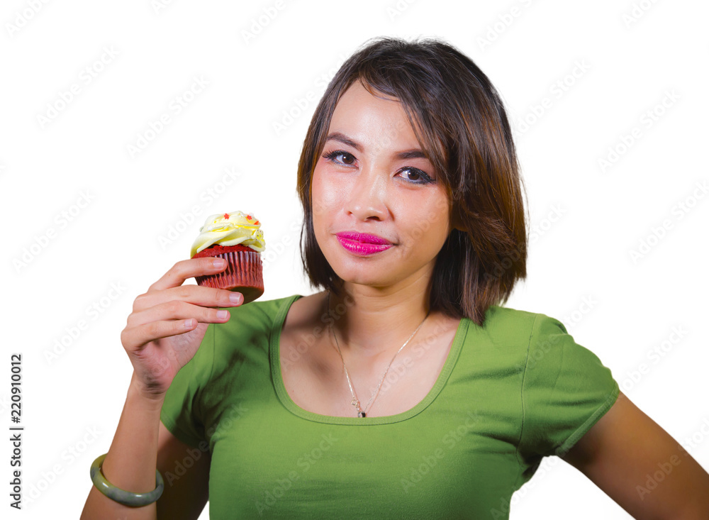 young beautiful and happy hispanic woman eating tasty and delicious yellow sugary cupcake posing on isolated background in sugar and sweet addiction young beautiful and happy hispanic woman eating tasty and delicious yellow sugary cupcake posing on isolated background in sugar and sweet addiction
