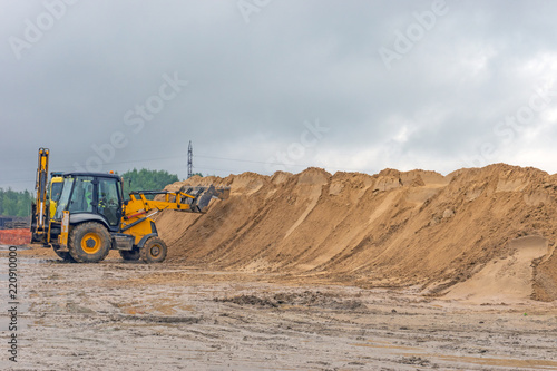Bulldozer at a construction site forms a pile of sand