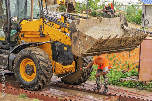 Driver at the construction site washes the excavator on the overpass