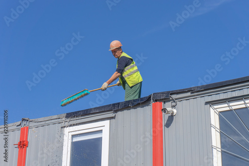 Worker at the construction site cleans the roof of the water with a brush