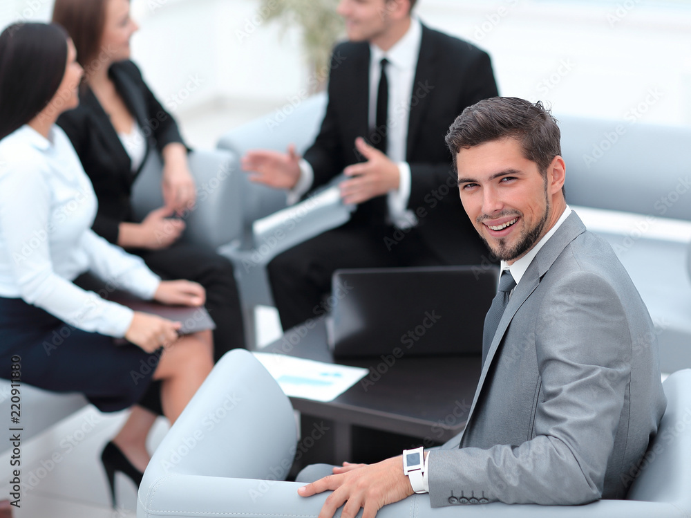 businessman sitting in an office on the background of business team. businessman sitting in an office on the background of business team.