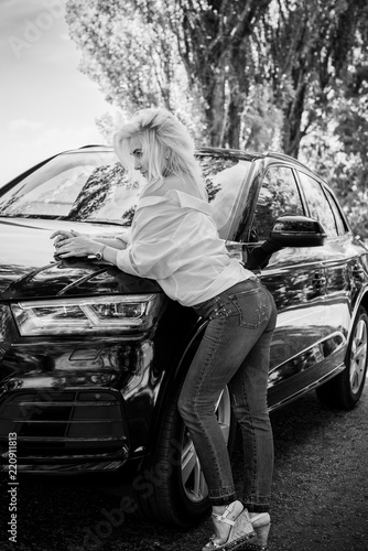 European woman sitting in car, lady driving automobile, outdoors portrait. Young woman driving on road trip on beautiful sunny day. Concept of women and auto 