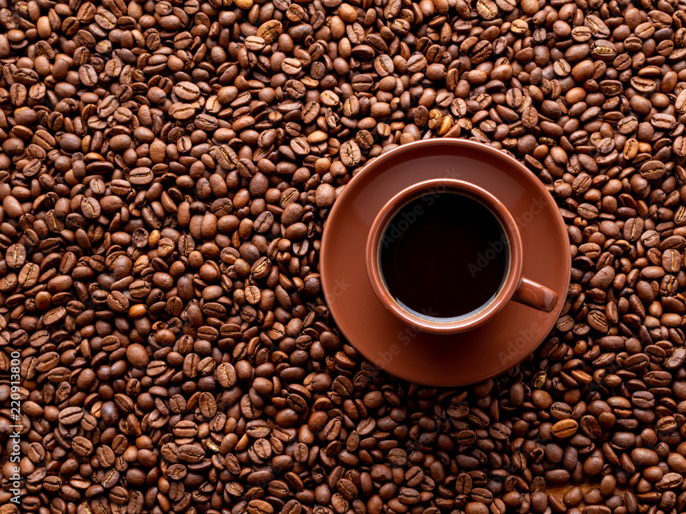 brown cup of espresso on background of scattered coffee beans, top view, copy space