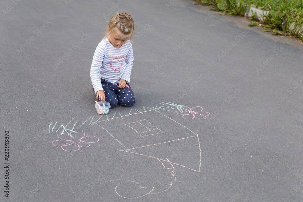 Naklejka premium Preschool caucasian girl drawing a house with chalks on the pavement