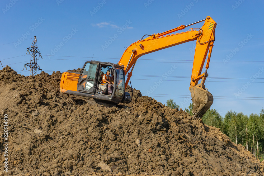 Orange excavator loads the land on a construction site.. Orange excavator loads the land on a construction site..
