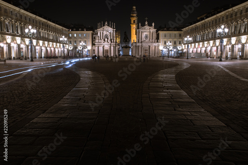 One of the main squares of Turin, Piazza San Carlo, photographed at night while the headlights of the bikes whiz past the historical monuments of the city