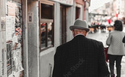 An elderly gentleman, taken back with a gray hat, walks along the canals of Venice