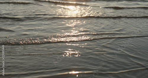 closeup of small waves with caustics on a beach at sunset