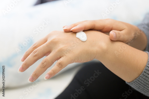 Closeup of young woman applying hand cream