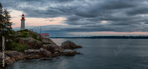 Lighthouse on a rocky shore during a vibrant cloudy sunset. Taken in Horseshoe Bay, West Vancouver, British Columbia, Canada.