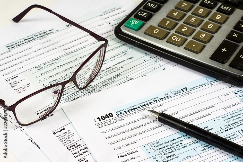 Tax Form 1040 pen and glasses on a background of a calculator and glasses, close-up Tax Form 1040 pen and glasses on a background of a calculator and glasses, close-up