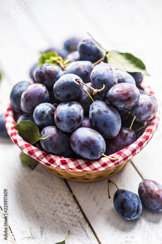 Sweet ripe plums in basket on garden table