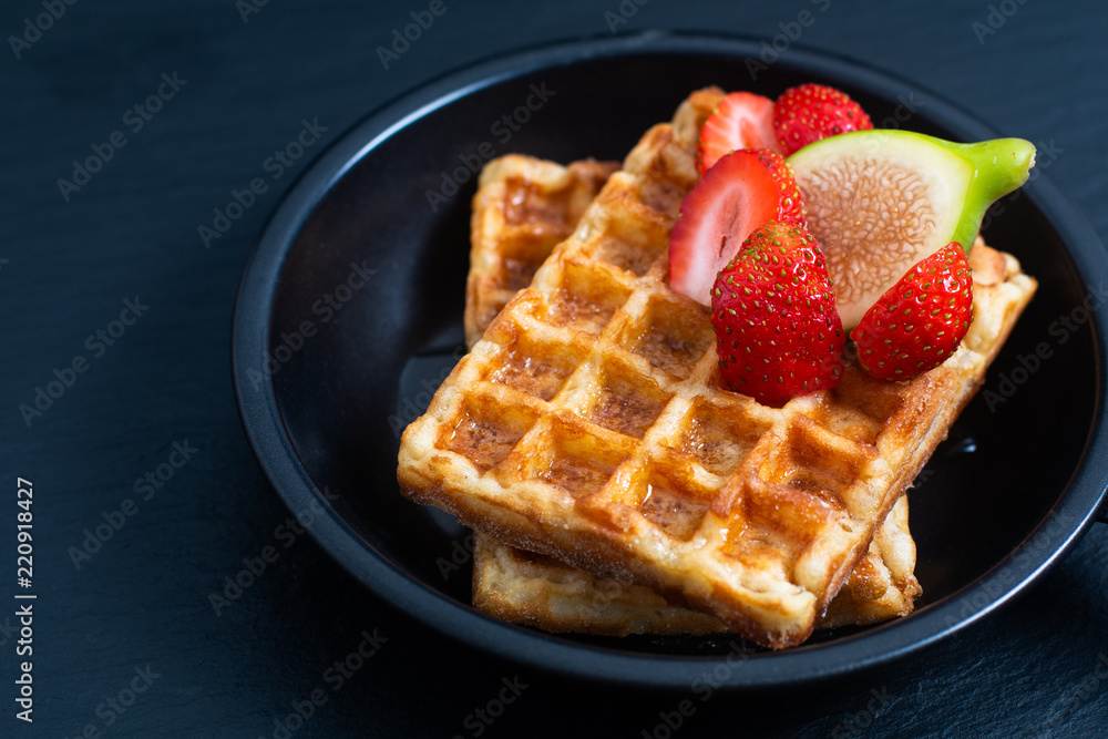 Food concept square Waffles and syrup with strawberry and fig topping in iron pan with copy space Food concept square Waffles and syrup with strawberry and fig topping in iron pan with copy space