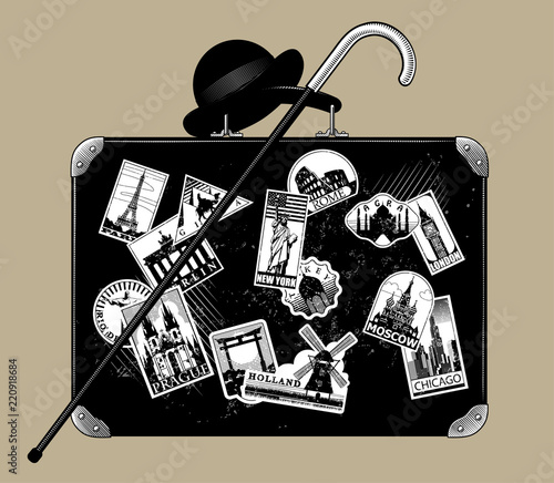 Old black suitcase with walking stick, bowler hat and travel labels