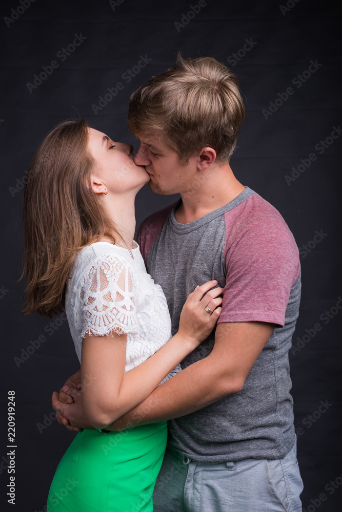 Beautiful young couple hugging and kissing isolated on black background. Beautiful young couple hugging and kissing isolated on black background.