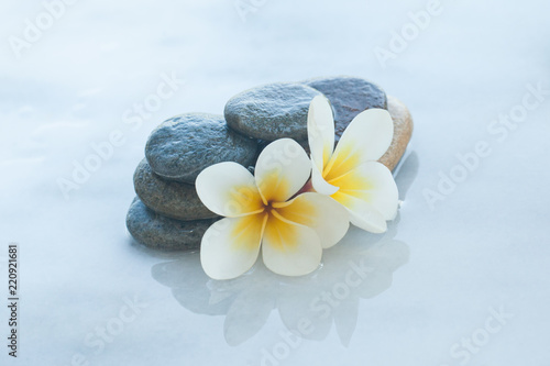 spa set with flowers and stones on white marble table outdoors.