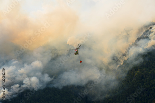 Aerial firefighting with helicopter on a big wildfire in a pine forest