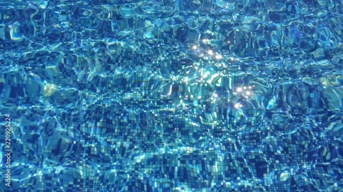 Mosaic bottom of the pool. Abstract blue water background in slow motion. 4x slow motion, 120 FPS shot of water. Brilliant Sparkles From Sun on blue pool water surface
