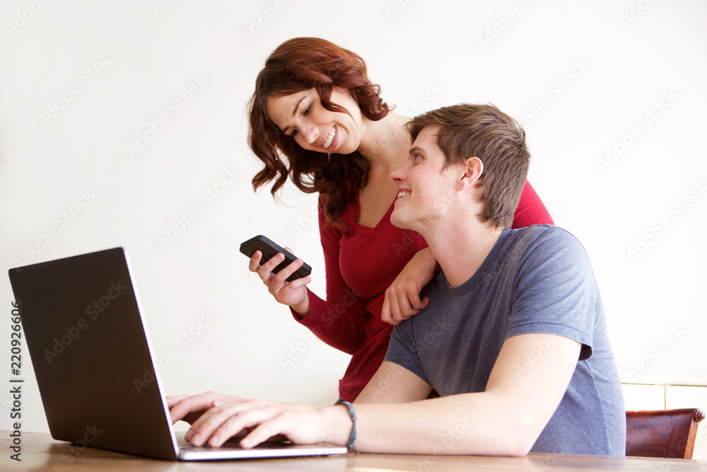happy boyfriend and girlfriend using laptop computer and mobile phone