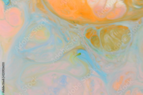 Fluid art. Abstract orange green background on liquid. Multicolored stains of paints. Blurred pattern for designer. Contemporary Art