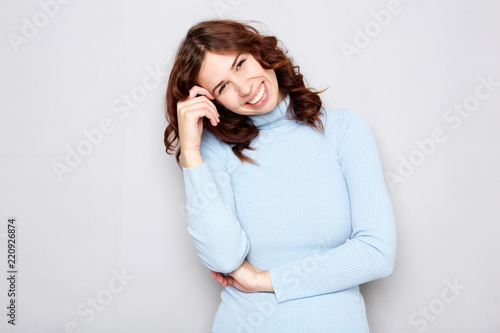 attractive young woman smiling against gray background