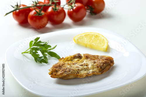 One pork brain schnizel on plate with a lemon slice photo