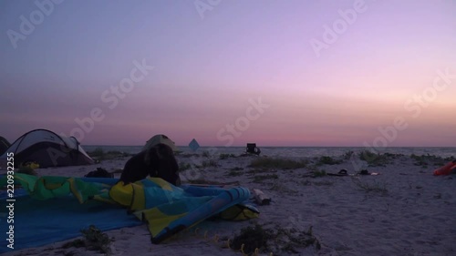 A girl at dawn is laying out a training kite on the beach photo