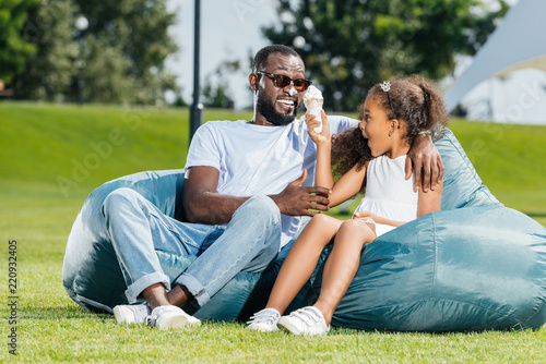 african american daughter having fun with ice cream while sitting on beanbag chairs with father © LIGHTFIELD STUDIOS