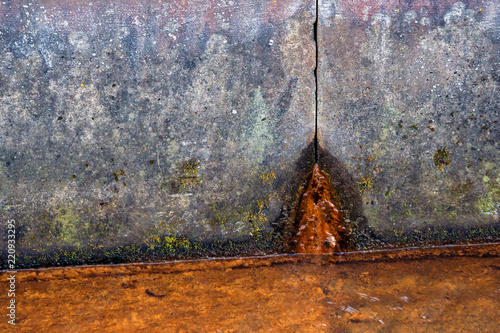 two concrete slabs of dirty gray color in spots, rusty water flows from the hole from below, in the foreground there is a liquid rusty from corrosion, a gloomy look, design, background, daylight,