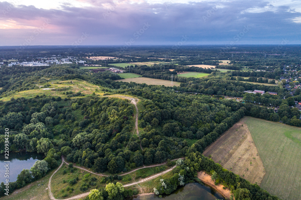 Aerial view of amazing sunset over the park in Germany. Hill and lake from birds eye view.  