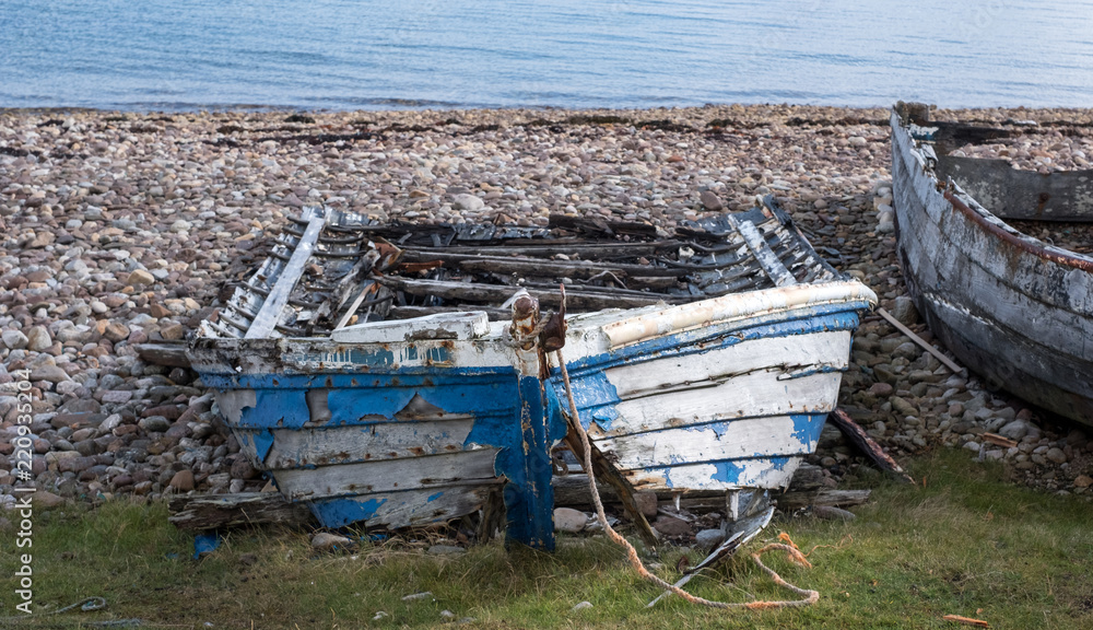 Ruins of small boat on the beach at Polbain, north of Ullapool. In background, view of the Summer Isles taken from the Scottish mainland on the west coast of Scotland. 