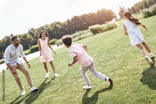 Bonding. Family of four running on grassy field playing playing 