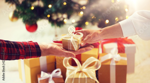 holidays, presents, new year and celebration concept - close up of couple hands giving and receiving christmas gift box photo