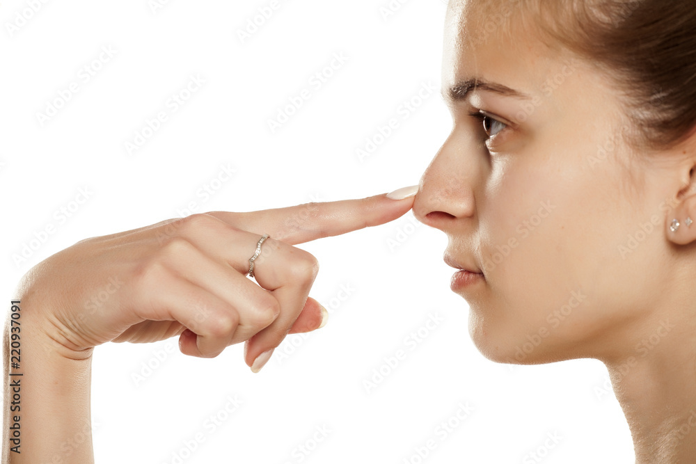 Profile of young woman touching her nose on white background Profile of young woman touching her nose on white background