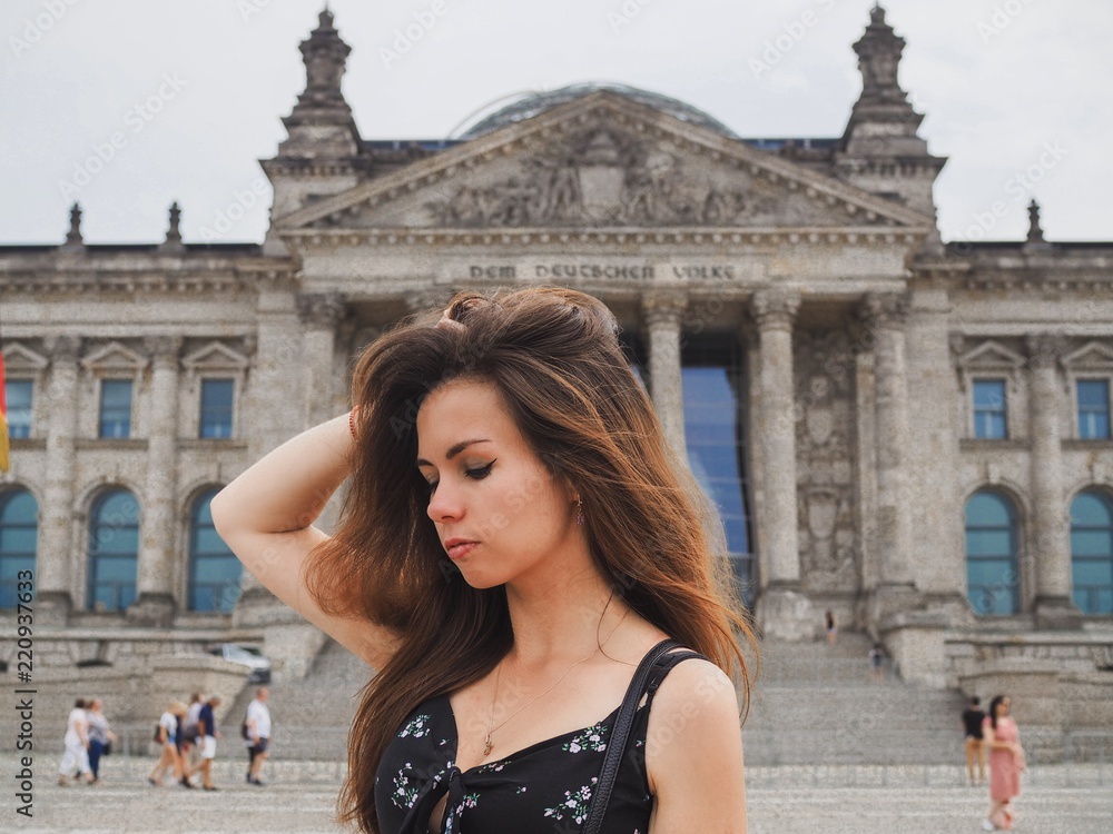 The girl with long hair in black dress standing in front of German Parliament, building of the state assembly in Berlin