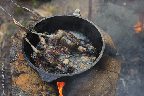 Cooking fried woodcock or snipe in hot butter with red currant. Outdoors.