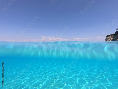 Underwater photo of tropical paradise turquoise exotic beach of Voutoumi with sail boats docked in island of Antipaxos, Ionian, Greece © aerial-drone